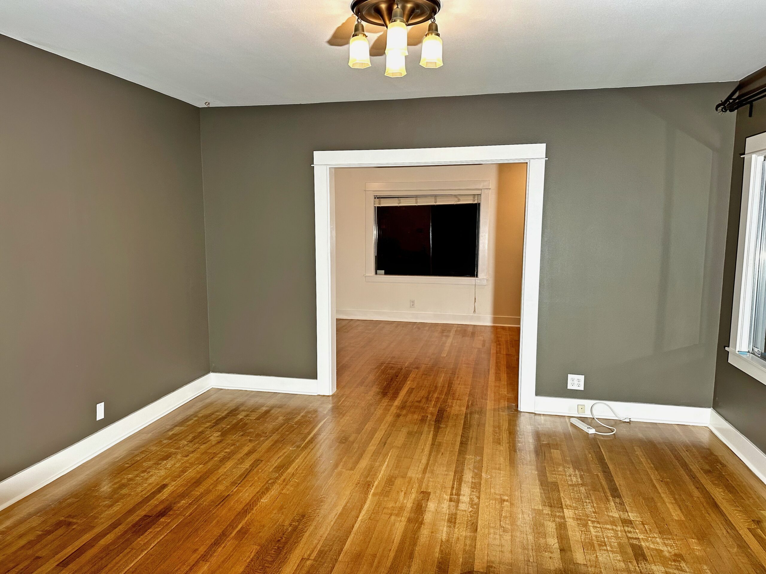"Interior view of a room with walls painted in a rich taupe shade, complemented by bright white trim around the windows, door, and baseboards by Paintitrightpro."